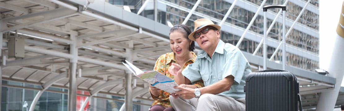 A senior Asian couple sitting on the stairs, holding a map.